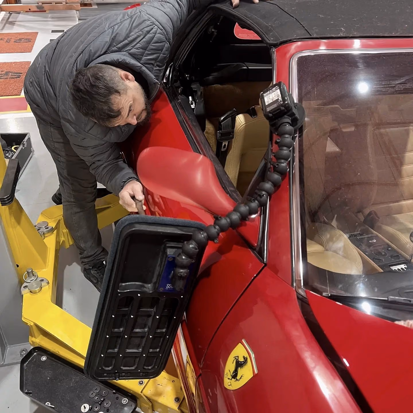 Técnico reparando a lateral de uma Ferrari vermelha com prancha de luz